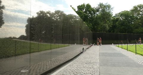 Washington DC, USA - June 25, 2018: People pay tribute to the lost soldier names inscribed on the Vietnam Veterans War Memorial on the National Mall