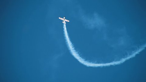 Aviation holiday, air show. Pilotage aircraft plane performs aerobatics dizzying stunts in the blue sky over many admired viewers