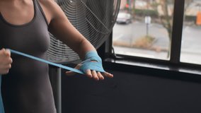 Close up of a female boxer expertly tying hand wraps around her wrists in a gym - Powered by Shutterstock - Get 15% off with code: PIKWIZARD15