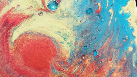 Colorful sparkling paints mix in beautiful patterns. Oil ink of coral, orange, yellow, blue and other colors spread on the surface and mix one into another creating amazing textures and design.