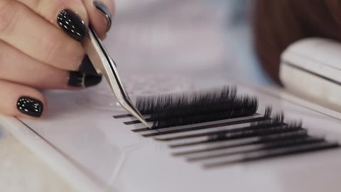artificial eyelashes, the hand holds tweezers and holds on the eyelashes