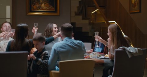 Family having a video call with relative during thanksgiving dinner, happy family greeting a remote guest. 4K UHD 60 FPS SLOW MOTION Blackmagic RAW Stock Video