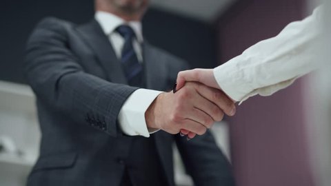 Hiring, man in a suit, a businessman shaking hands with a woman colleague, a handshake in the office.