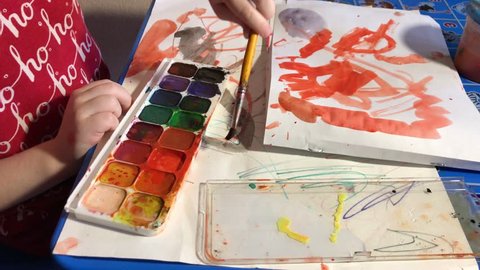 child paints with watercolors.
