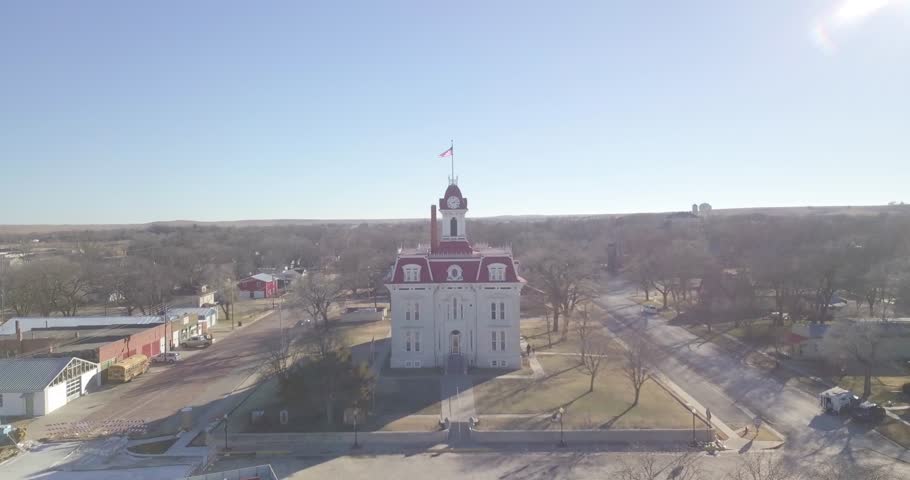 An aerial flight over over a limestone courthouse and a limestone mansion in the Kansas prairie during winter.
