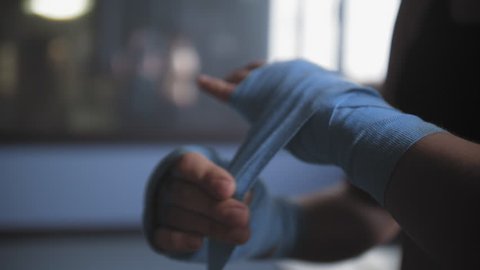 Close up of a female boxer tying hand wraps around her wrists before a workout