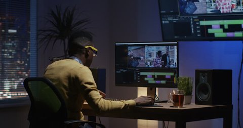 Medium shot of a young man sitting back and editing a video inside a modern video studio