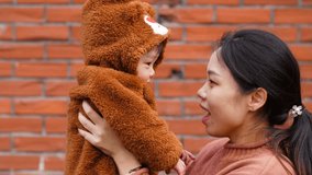 Young asian woman playing with her baby boy outdoor, young Chinese mother holding her little kid son in arm looking at him at winter time,  lovely Chinese family lifestyle 4k slow motion clips
