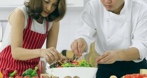 Close up scene video of Asian chef and Asian woman student preparing salad in cooking class together.
