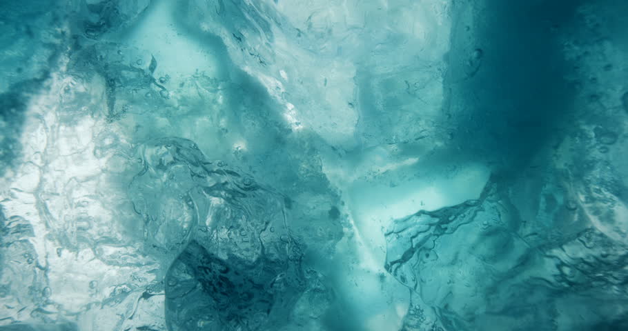 Underwater ice with rising water bubbles. Macro shot of beautiful blue underwater ice.
