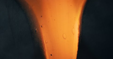 Hot molten lava stream on a dark stone background in slow motion. flowing liquid magma lava in 4K