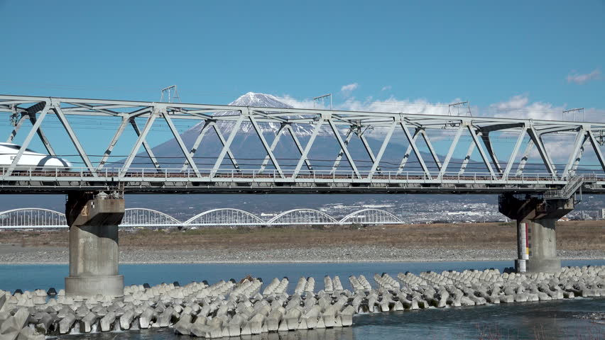 Shinkansen bullet train passing through Mount Fuji and the Fujikawa bridge, Shizuoka. Japan