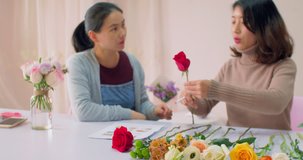 Close up of Asian female florist communication to a client with a flower in hand, teaching explaining to the customer, selling flowers, learning small business, flower lifestyle 4k clip.