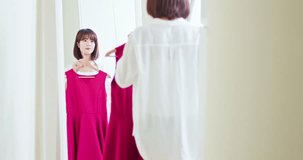 asian girl trying the dress and looking herself in mirror cheerful