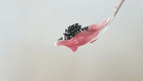 Close-up of dripping blackberry yogurt with spoon in slow motion 120 fps