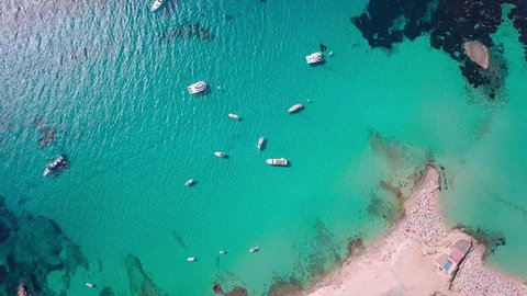 Flying in a circle above beautiful bay on Ibiza with beach, yachts and clear blue sea 4K