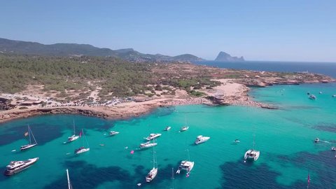 Flying away from beach on Ibiza with beautiful clear water and yachts