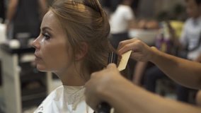 Hairstylist using hair iron and comb for woman hairstyling in beauty  studio. Hairdresser creating female hairdo with hair tongs and comb in barber shop. Woman hairstyle concept. Beauty and style