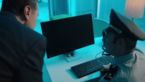 Police detectives working together in computer room to try and solve a case . Men at desk in room with data on screens .  You can insert and track your picture or video inside monitor . Slow Motion .
