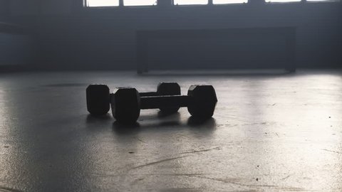 Camera zooms in on a two hand weights lying on the floor of a gym