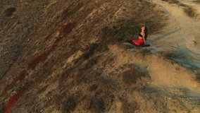 Beautiful view of woman doing yoga stretching on the edge of huge mountain sunset.
