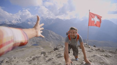 Young man hiking in the Swiss Alps, hand reach out to help. Helping hand, couple hiking on mountain top hand reaches out for assistance. Slow motion