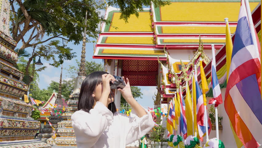 Young Asian woman tourist solo traveller taking pictures in colorful Thai temple, Bangkok Thailand