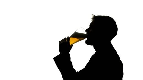 Man pours beer into a glass goblet and drinks . Side view. Silhouette White background