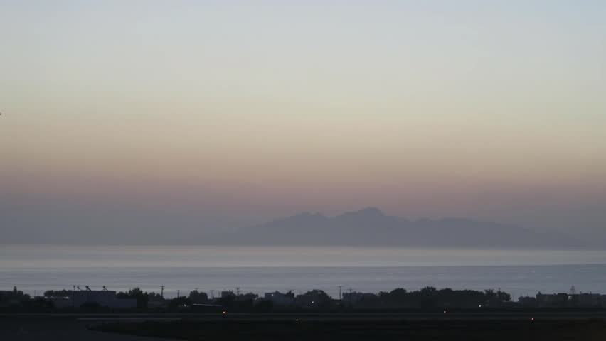Airplane flying across the mountain site at sunrise early in the morning at Chania airport in Crete, Greece