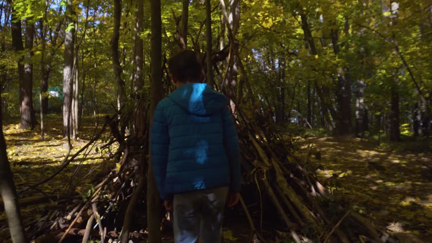 Teen young boy playing in hut of branches