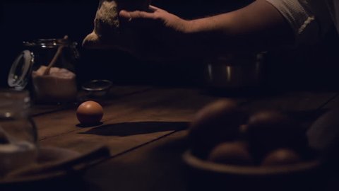 Slow motion footage of a man’s hand putting a bag with flour on a wooden table 