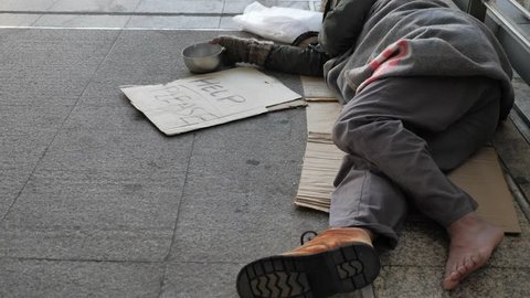 Homeless old man in dirty clothes sleeping on the street and asking for help