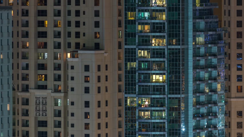 Glowing windows in multistory modern glass residential building light up at night timelapse. People in apartments. Skyscrapers illuminated at evening. Dubai Marina and JBR, UAE. | Shutterstock HD Video #1022999686