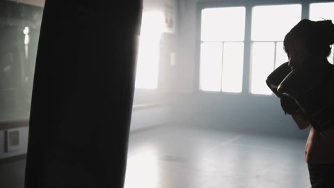 A female boxer beats into a punching bag while training in a boxing gym