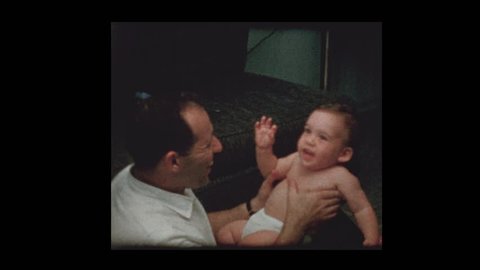 Young dad kisses loves and plays with baby son 1960