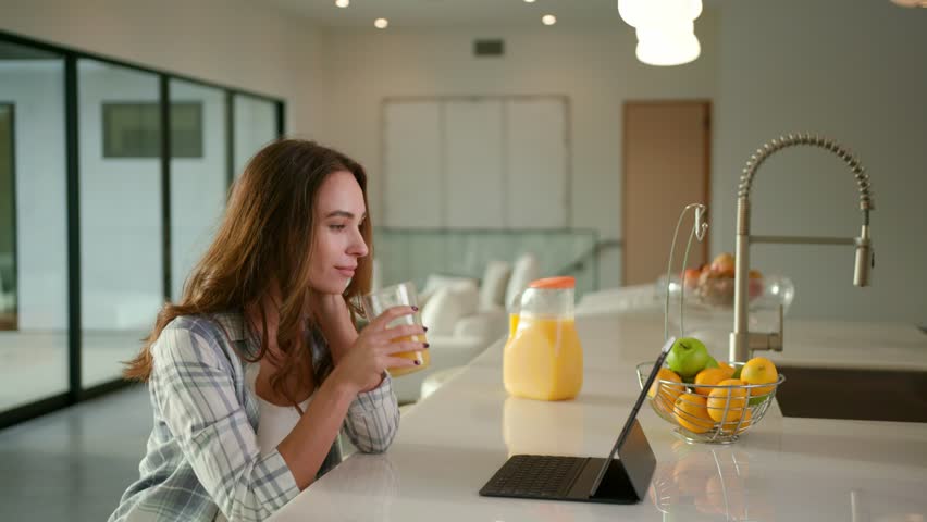 Woman drinking an orange juice at modern kitchen in contemporary house 