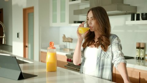 woman drinking an orange juice at modern kitchen in contemporary house 