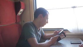 Casual man reading from mobile phone screen while reads sms message traveling on train wagon. slow motion video. Wireless social media internet web on public transport concept. train wagon compartment