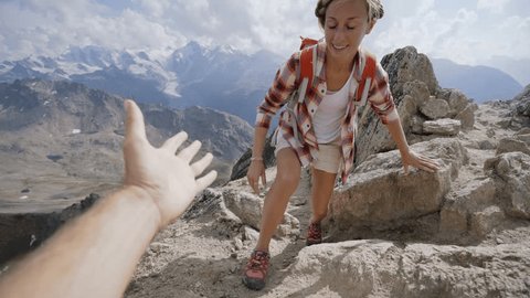 Teammate helping hiker to reach summit. Couple hiking in Switzerland, hand reach out to help female hiker reach the summit. A helping hand concept.