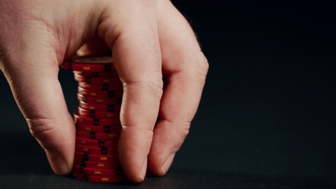 A stack of red poker chips slides in on a black background. At the end the hand takes them away. 