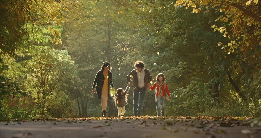 Young asian family of four walking down the road in golden autumn park, cheerfuly smiling - 4k Royalty-Free Stock Footage #1023025348