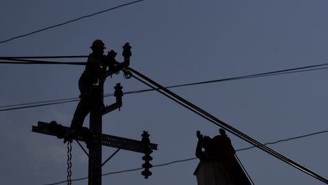 Silhouette of Electrician are installing high powered electric cables 
