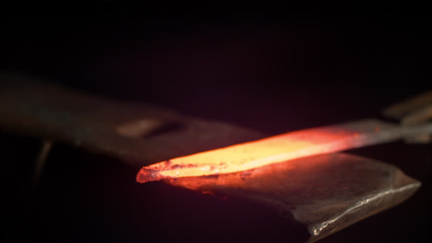 SUPER SLOW MOTION, MACRO, DOF: Metalworker forging a hot piece of metal into a beautiful knife blade. Cinematic shot of a glowing blade getting struck by a large hammer. Craftsman manufacturing blade. Royalty-Free Stock Footage #1023034693