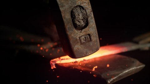 SUPER SLOW MOTION, MACRO, DOF: Metalworker forging a hot piece of metal into a beautiful knife blade. Cinematic shot of a glowing blade getting struck by a large hammer. Craftsman manufacturing blade.
