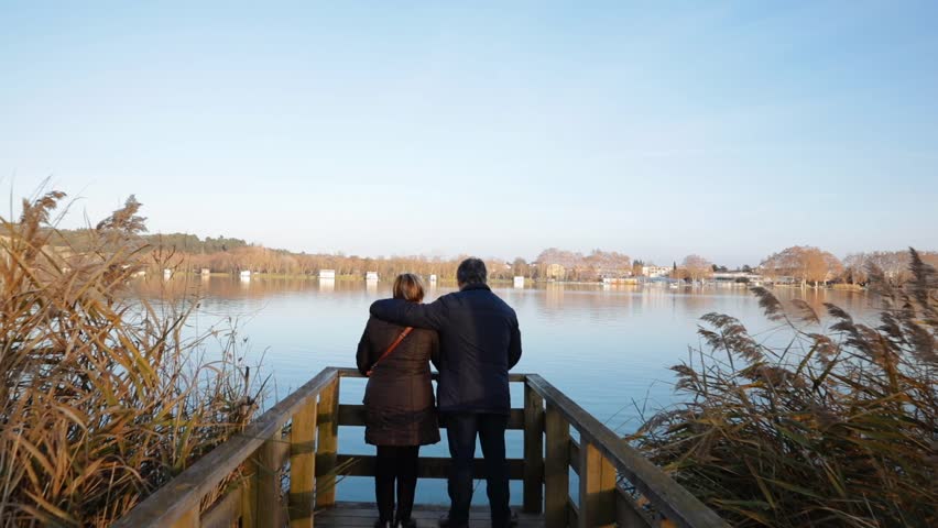 Senior couple contemplating a lake next to the pier