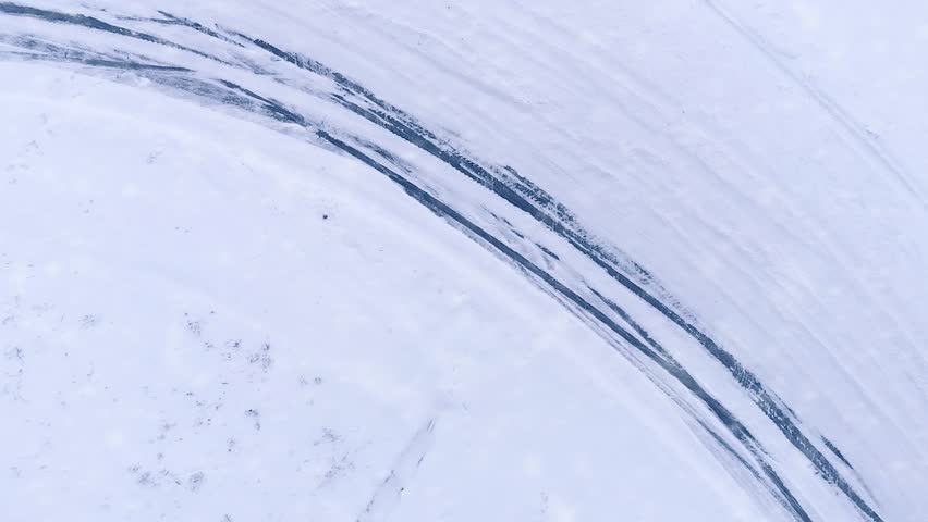 Aerial drone top view shot of car drifting on snow winter road 4k. Concept: Sliding on an ice, snow drifting, driving in the snow. Car racing on snow road track in winter, slide snowy winter road Royalty-Free Stock Footage #1023040000