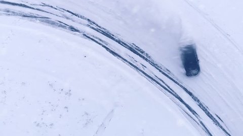 Aerial drone top view shot of car drifting on snow winter road 4k. Concept: Sliding on an ice, snow drifting, driving in the snow. Car racing on snow road track in winter, slide snowy winter road