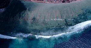 Drone footage of Nusa Penida, Indonesia with small village built on the east coast, waves are breaking over the pristine shallow coral reef and the algae cultures growing.