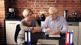Mature, worried couple sitting with documents in the kitchen
 - Powered by Shutterstock - Get 15% off with code: PIKWIZARD15