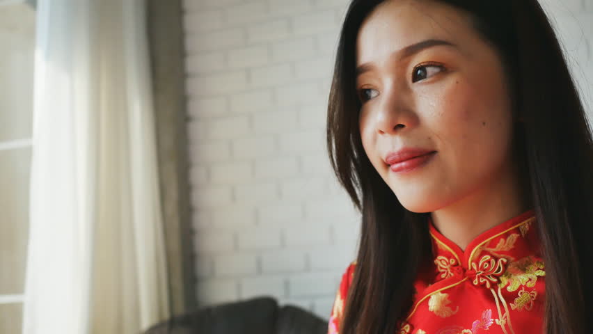Asian women dressing red dress in living room , Chinese new year concept